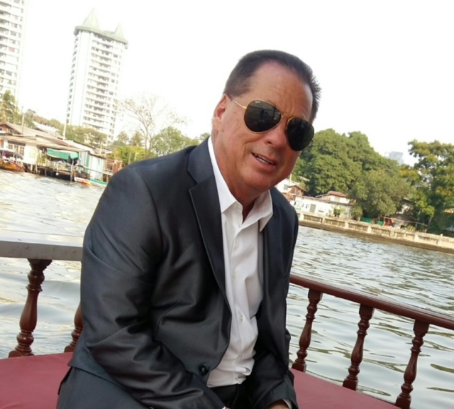 Man in suit sitting by the river.